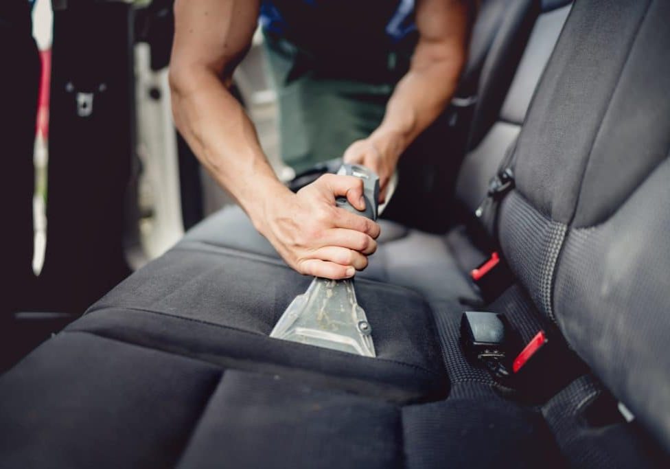 Professional detailer vacuums car seats